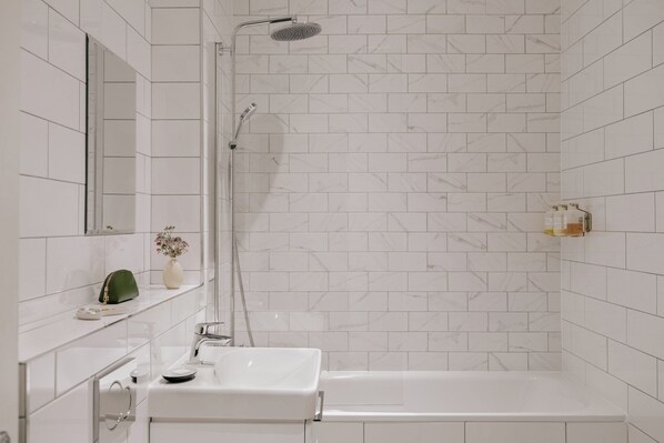 A modern bathroom with a white sink, a shower, and a mirror. - Royal Garden Apartments New Town (Edinburgh)