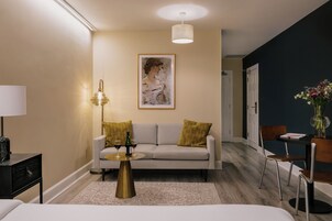Un salon moderne avec un canapé, une table basse, une lampe et une œuvre d’art encadrée accrochée au mur.