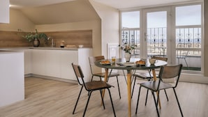 A modern kitchen with a dining area, wooden cabinets, and a view of the sea through large windows.