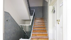 Una escalera con acabado de madera y barandilla blanca que conduce a una puerta blanca con picaporte de bronce.