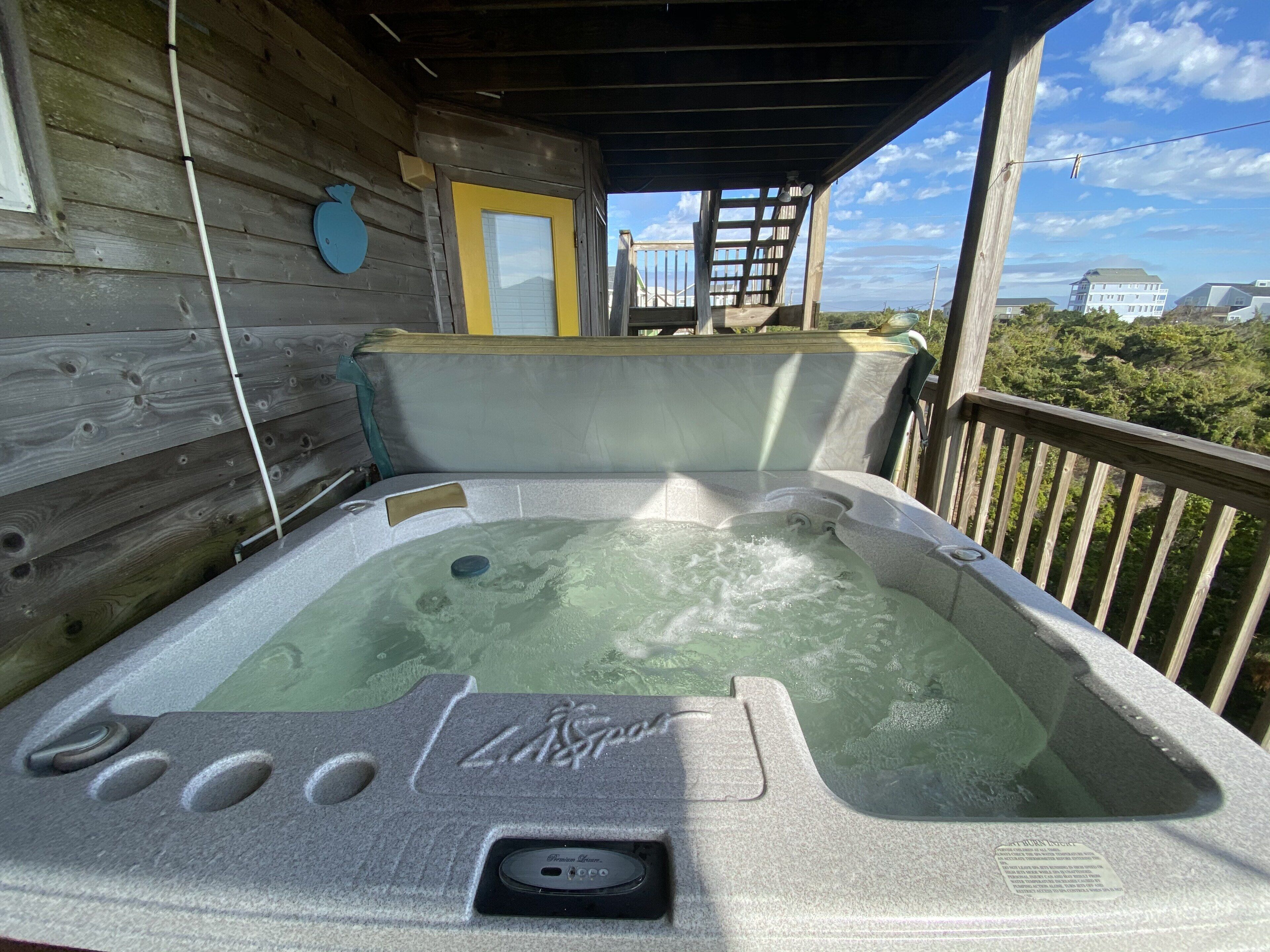 A hot tub with a stone exterior, a wooden deck, and a view of the surrounding landscape.