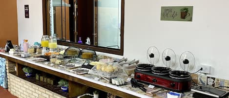 Montaje de bufé con diversos alimentos, una máquina de café y un espejo sobre la barra.
