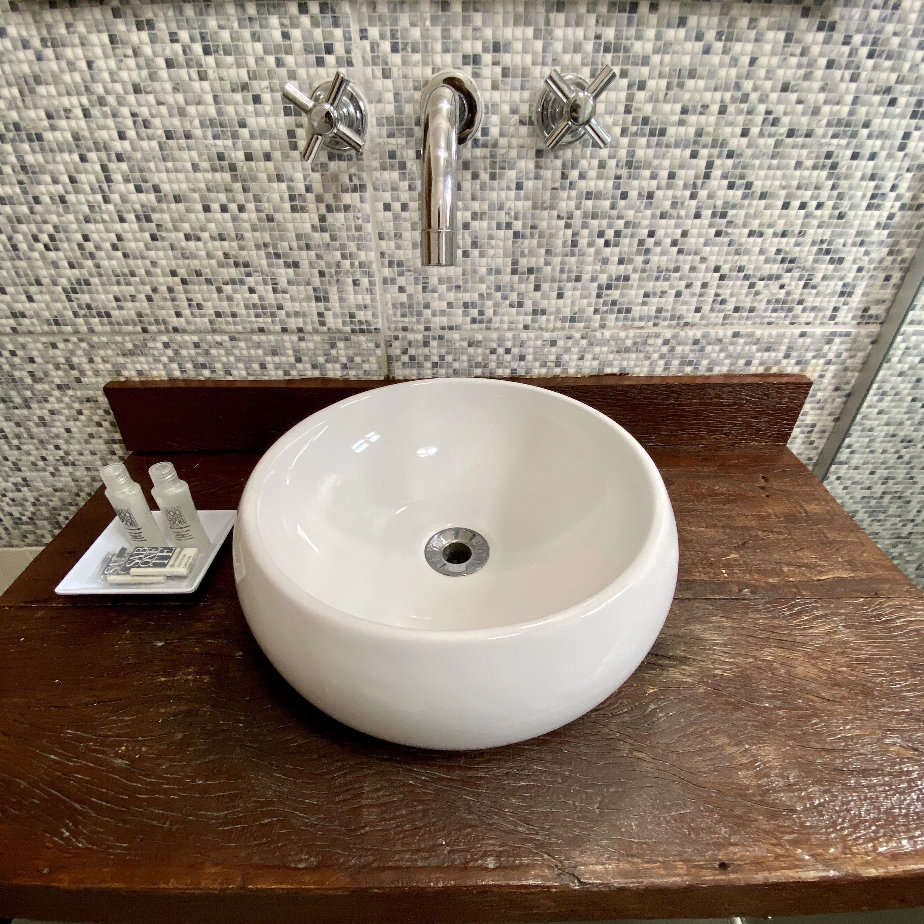 A white ceramic sink with a chrome faucet on a wooden countertop.