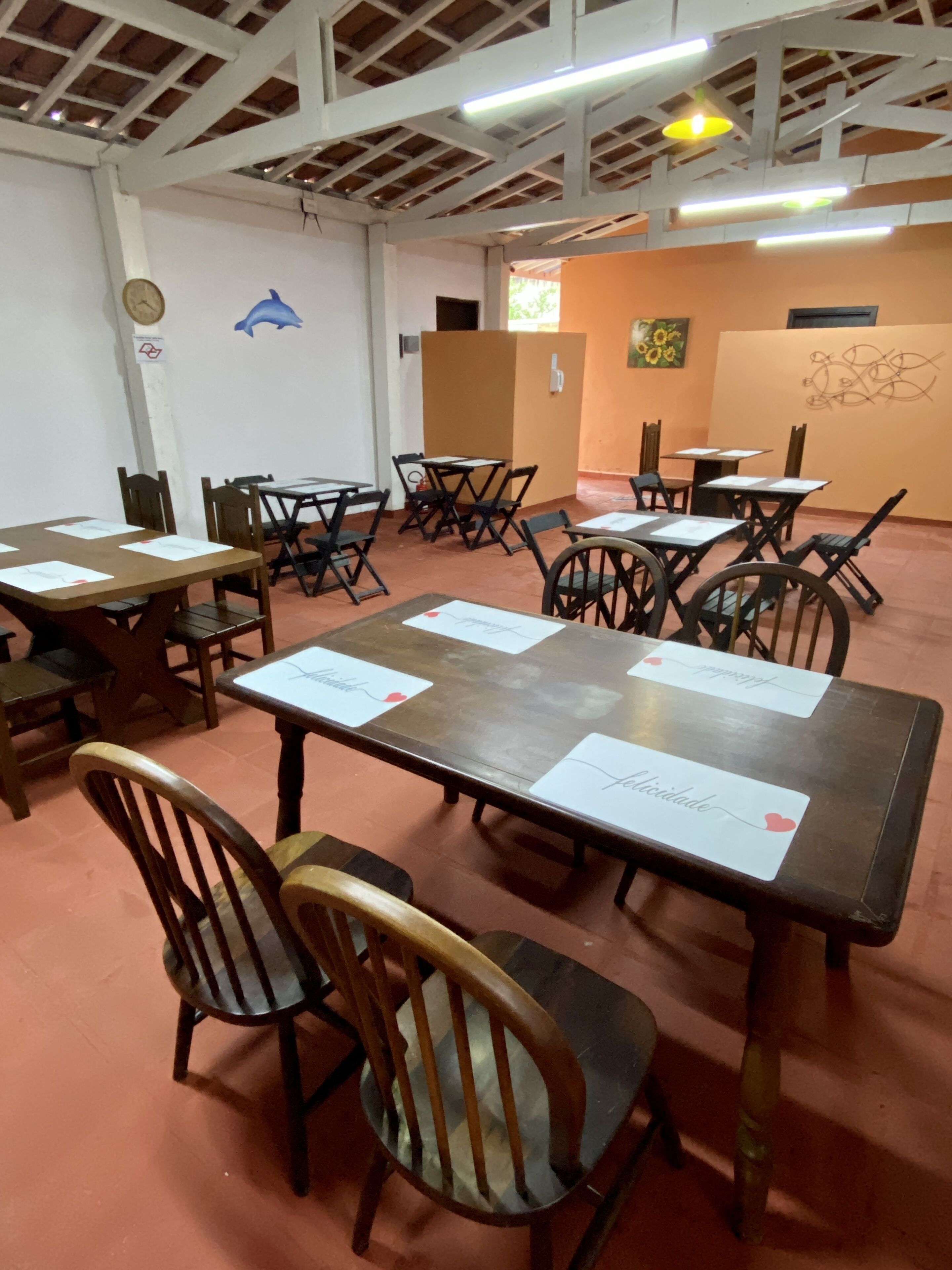Un salón de conferencias con mesas y sillas, paredes blancas y techo de madera.