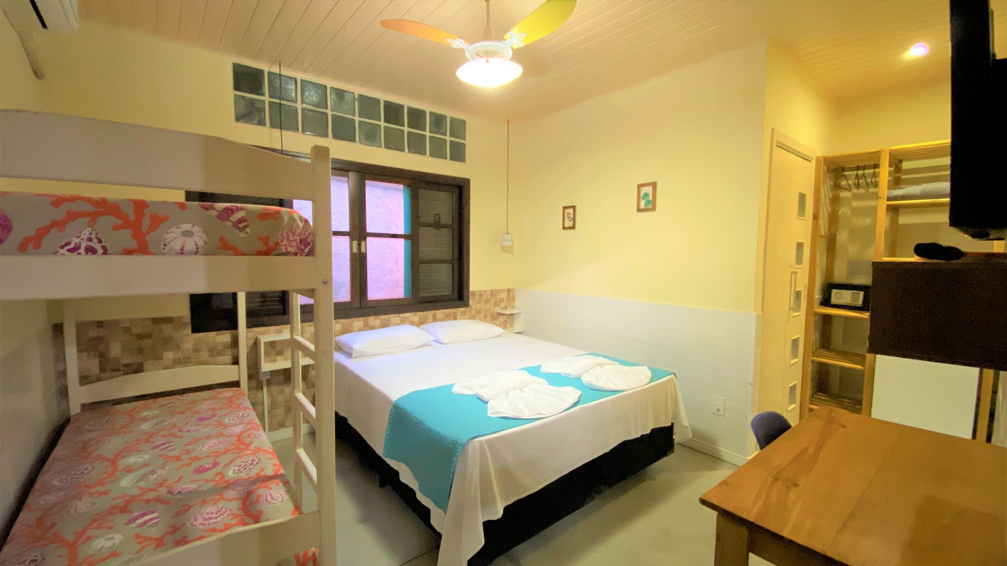 Una habitación con literas, una cama individual, un escritorio y un armario.