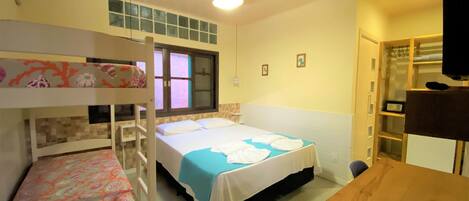 Una habitación con literas, una cama individual, un escritorio y un armario.