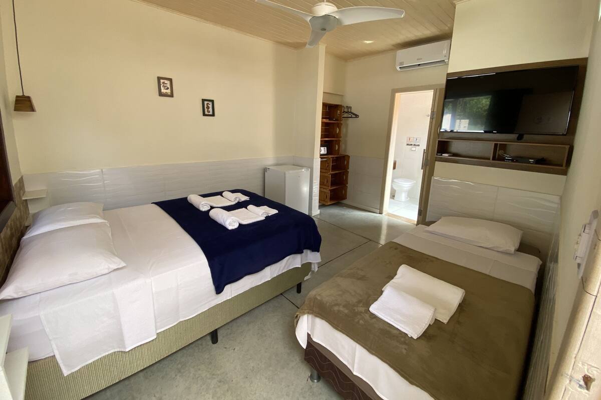 Una habitación de hotel con dos camas, televisión, aire acondicionado y ventilador de techo.