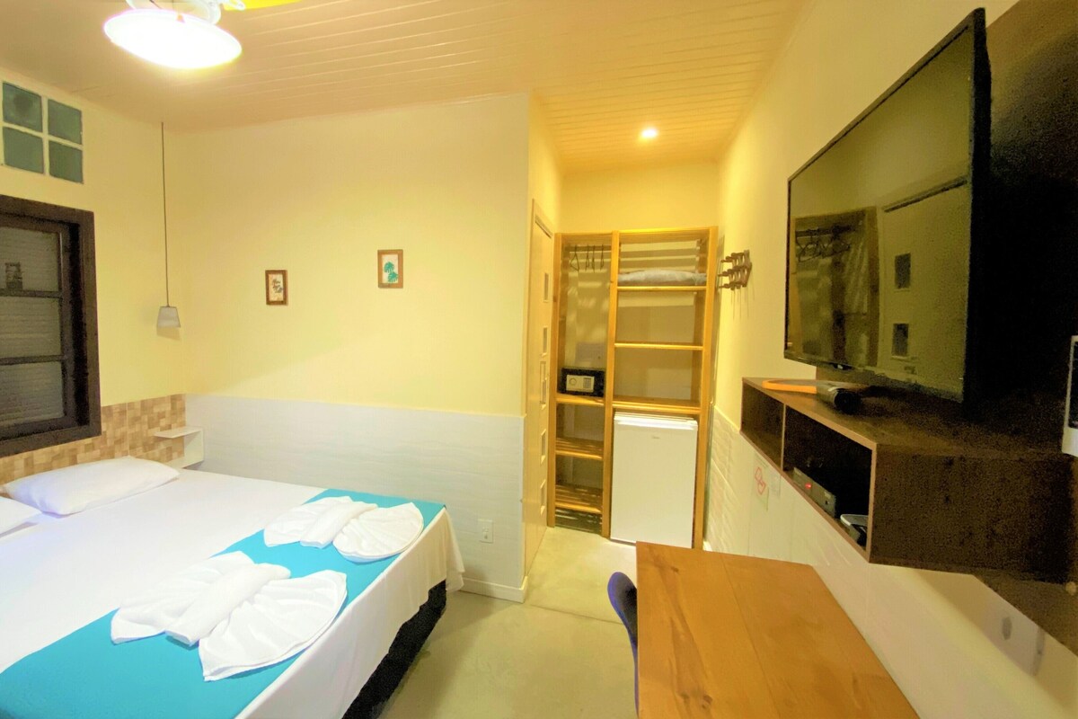 A hotel room with a bed, a desk, a TV, and a wardrobe.