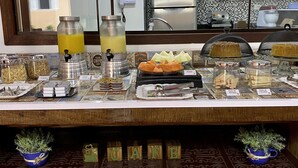 Un bufé de desayuno con diversas opciones de comida y un dispensador de zumo.