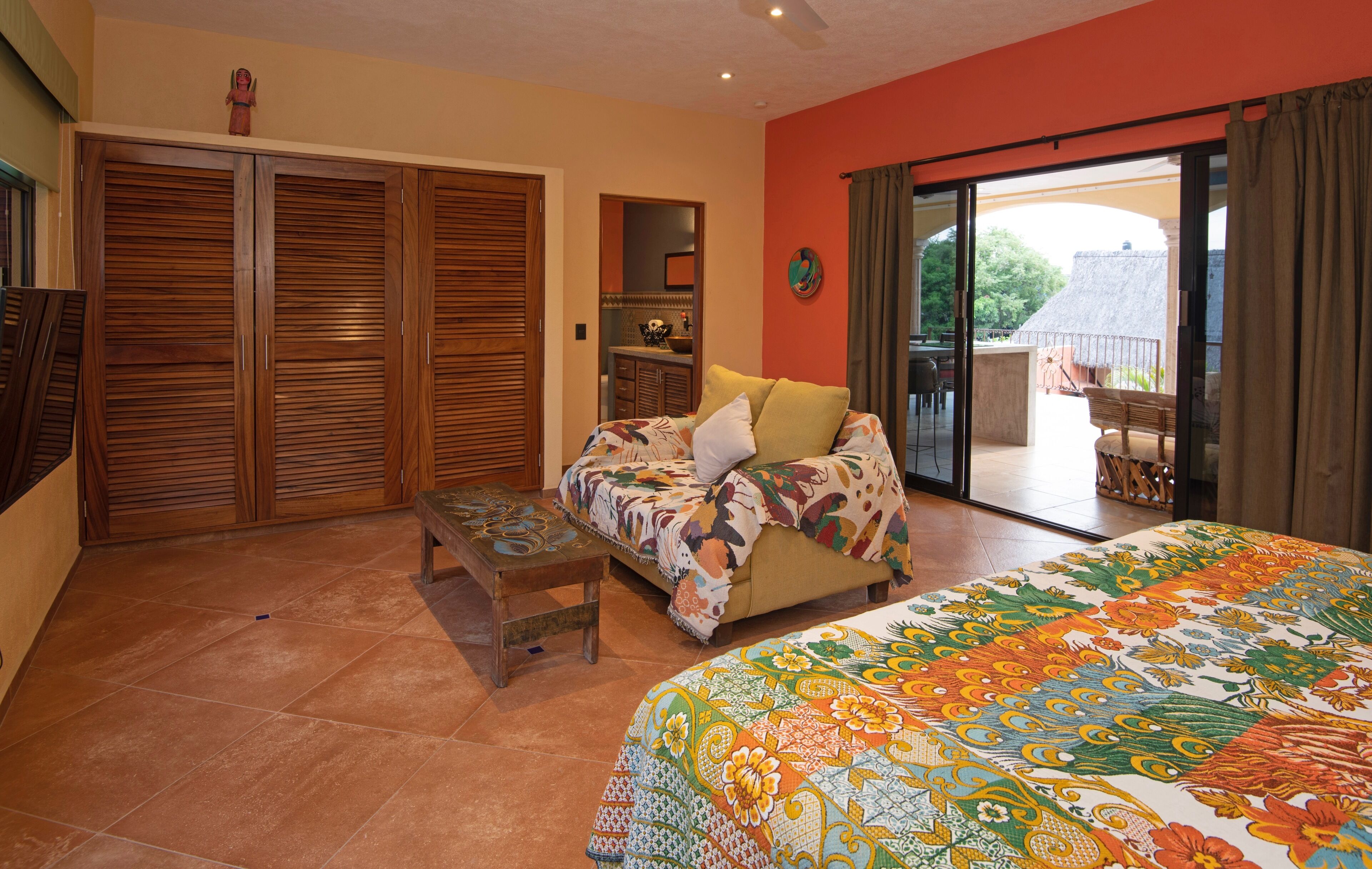 Une chambre à coucher comprenant un lit, un canapé, une petite table et une porte-fenêtre coulissante donnant sur un balcon.