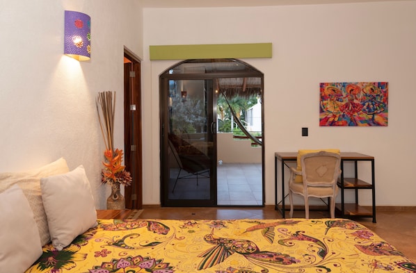 A room with a bed, a chair, a table, a door leading to an outdoor area, and a wall-mounted light fixture. - WATERFRONT COLONIAL PENTHOUSE 112m2 COMPLETE FLOOR &INFINITY POOL (Barra de Navidad)