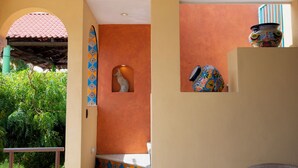 Une pièce avec un mur recouvert de carreaux, un vase décoratif et une fenêtre donnant sur un paysage verdoyant.