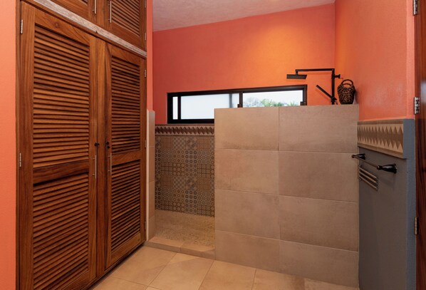 A bathroom with wooden cabinets, a tiled wall, and a window.