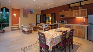 Une cuisine spacieuse avec des meubles en bois, une table à manger avec des chaises et une vue sur l’extérieur.