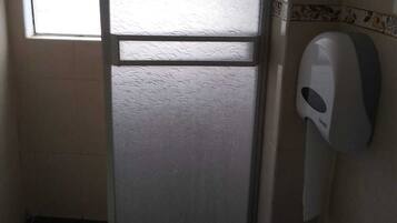 A small bathroom with a toilet, a hand dryer, and a frosted glass door.