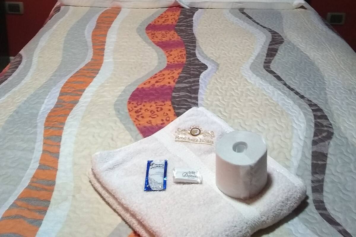 Una cama con ropa de cama a rayas, dos almohadas, una toalla y artículos de aseo en una habitación de hotel.