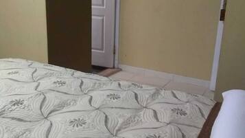 A bedroom with a bed, a door, and a wall with a light switch.