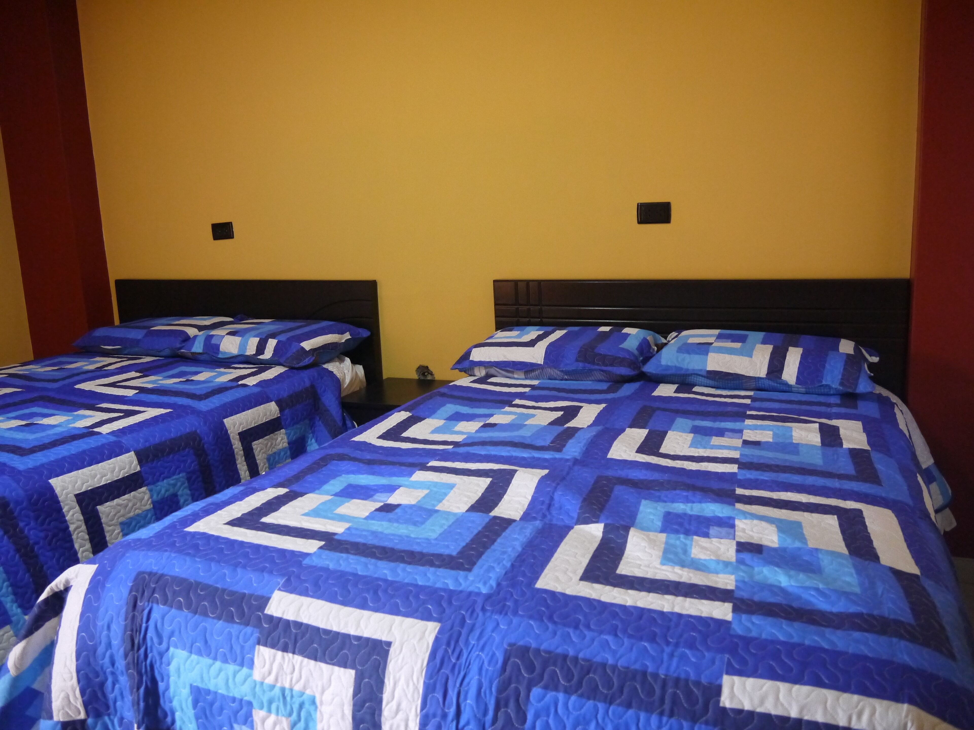 A hotel room with two beds, each with blue and white patterned bedding.
