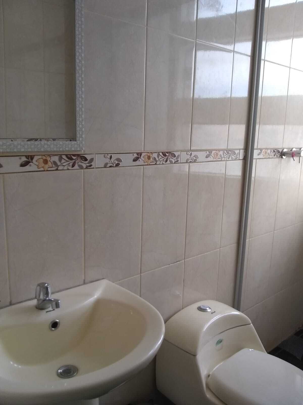 Un baño con lavamanos, inodoro y espejo.