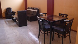 Un comedor con una mesa de vidrio, cuatro sillas, un sofá y un sillón reclinable.