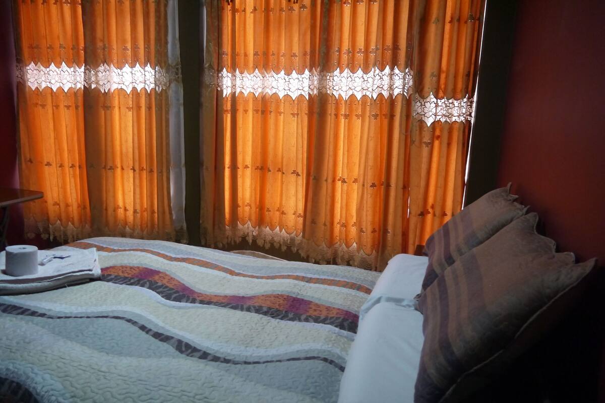 Una cama con colcha, almohadas y una caja de pañuelos.