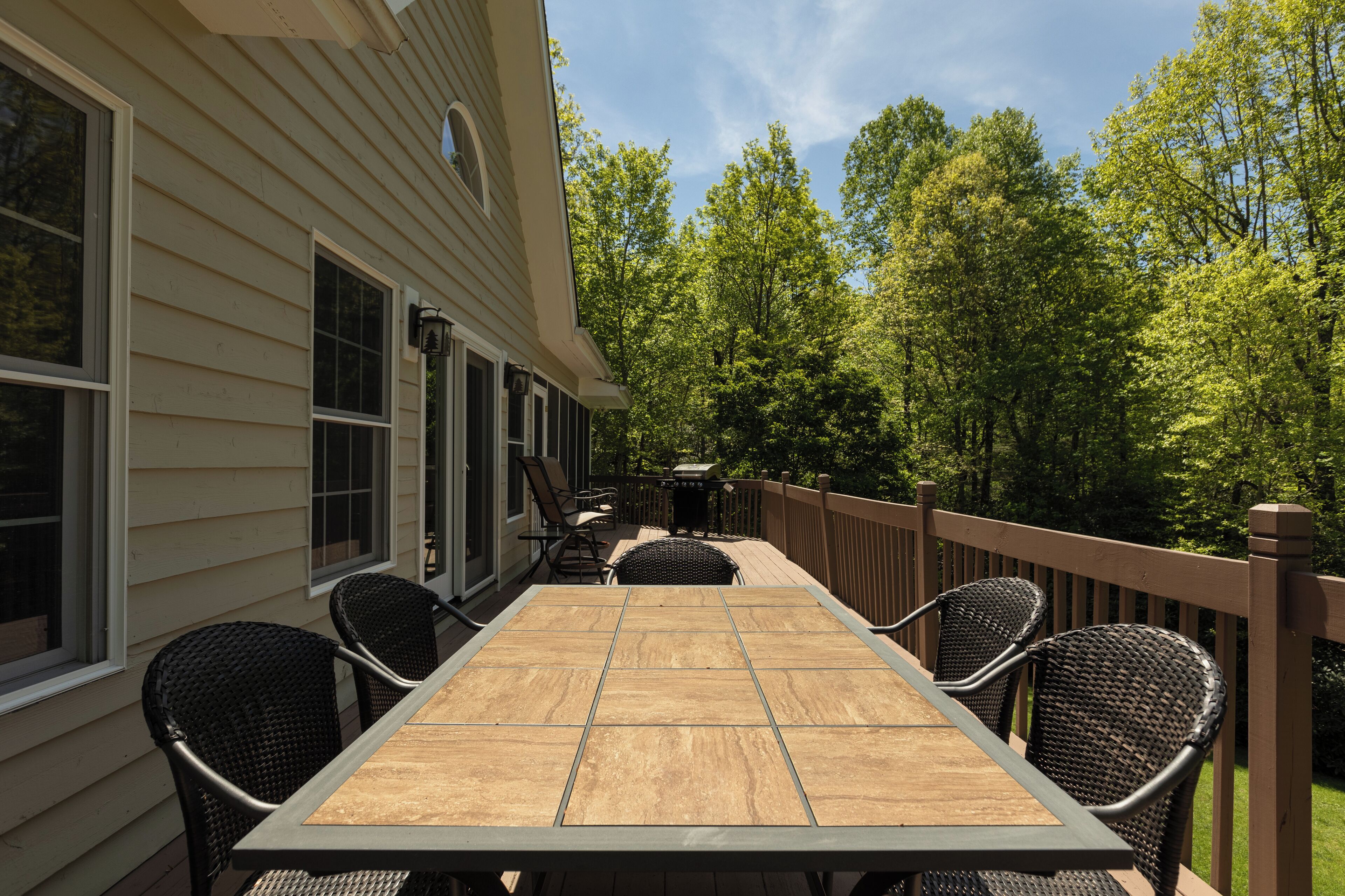 Une terrasse avec une table et des chaises, donnant sur une zone boisée.