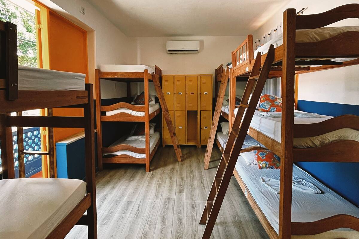 Asuntolan huone, jossa on kerrossängyt, puiset lokerot ja ilmastointilaite.