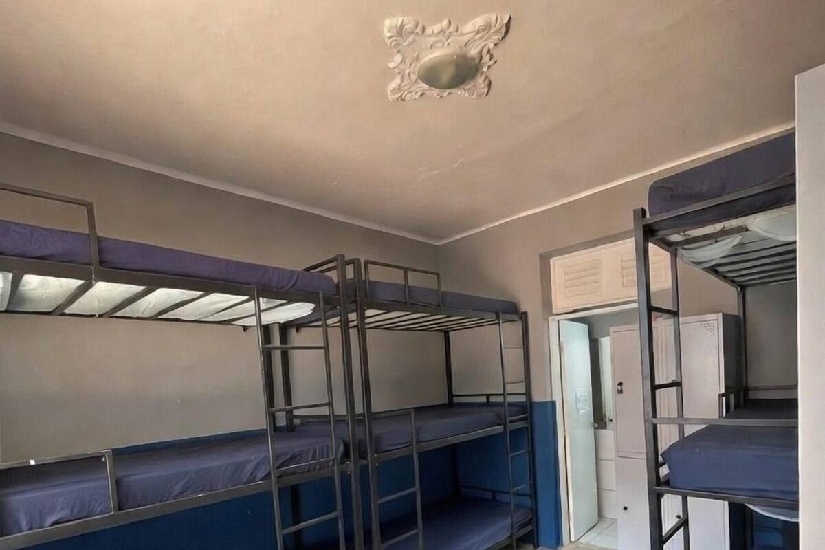 Asuntolan huone, jossa on kerrossängyt, valkoinen katto ja valkoinen ovi.
