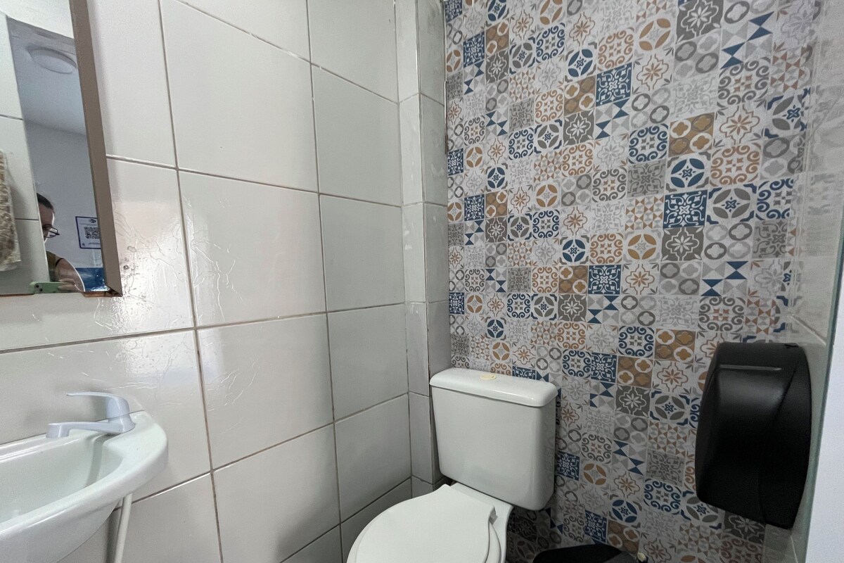 Baño con inodoro, lavamanos y pared de ducha con diseño.