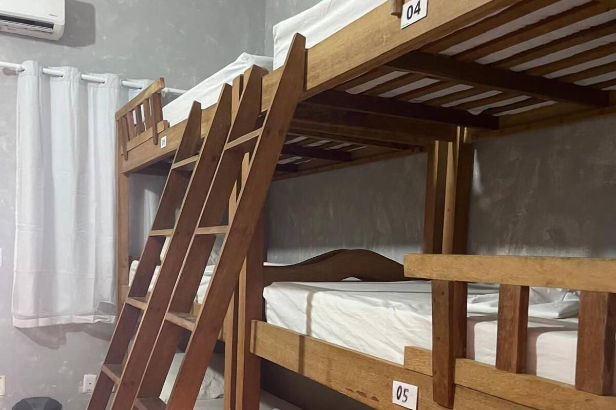 Kerrossängyllä varustettu huone, jossa on puukehikot, numeroituja sänkyjä ja tikkaat.
