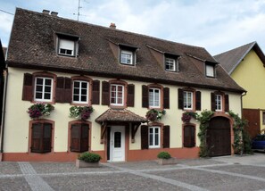 Een klassiek Europees gebouw met veel ramen, een centrale ingang en bloembakken.