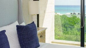 Een hotelkamer met een groot bed, een nachtkastje, een lamp en uitzicht op de oceaan.