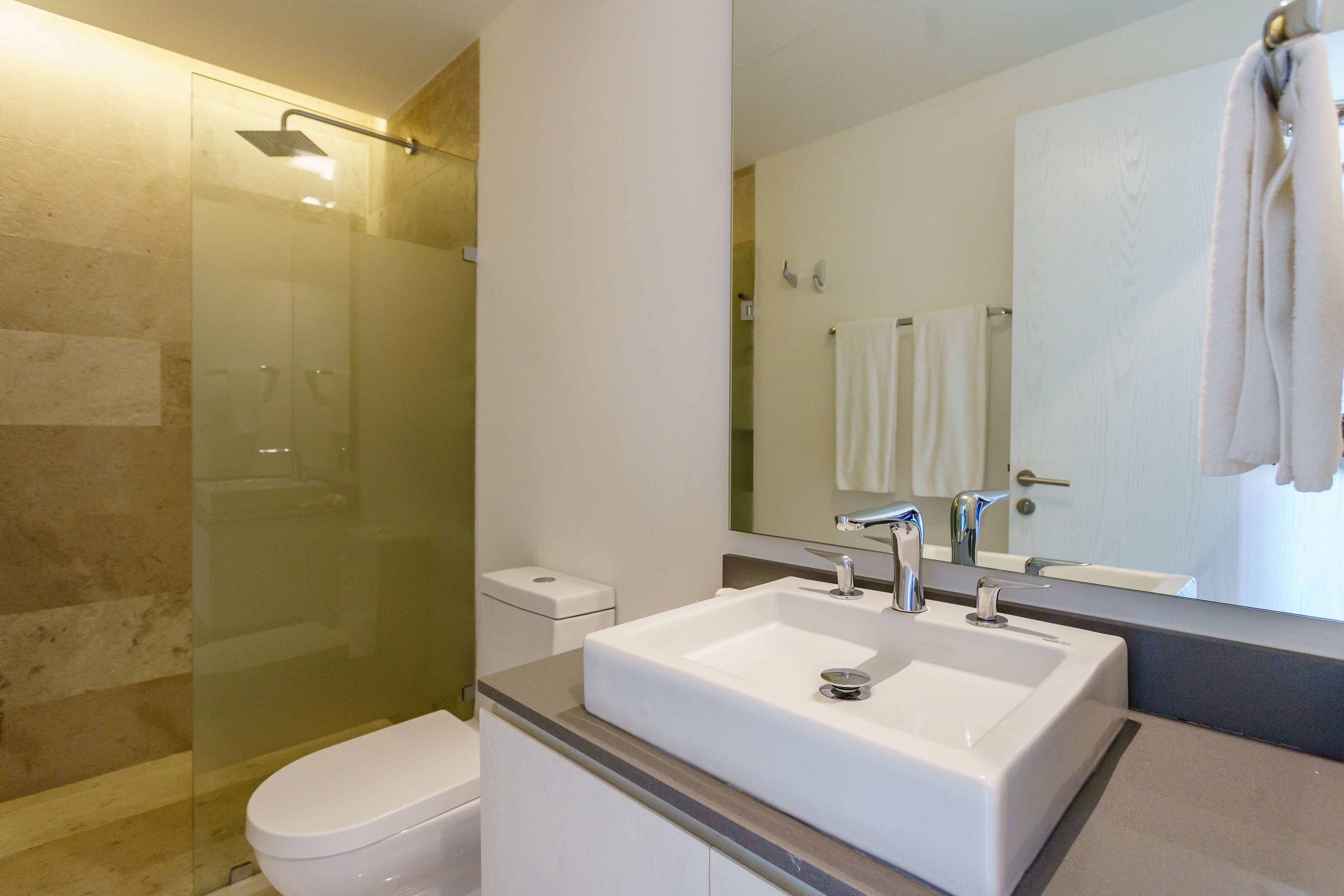 A modern bathroom with a glass-enclosed shower, a white sink, and a large mirror.