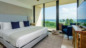 Een moderne slaapkamer met een groot bed, een bureau en uitzicht op de oceaan.