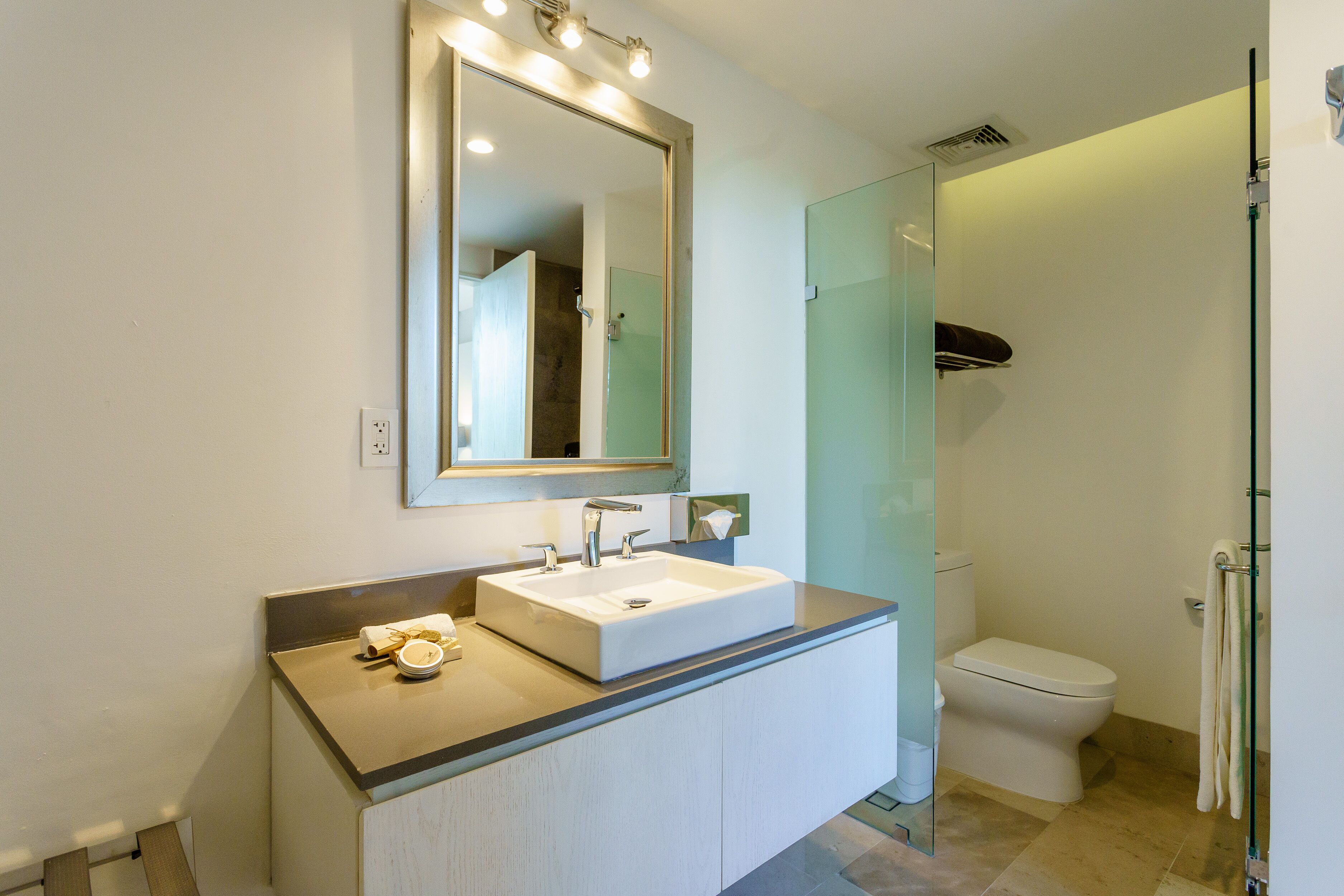 A modern bathroom with a large mirror, a white sink, and a glass shower enclosure.
