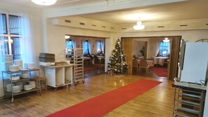 Una habitación amplia con alfombra roja, un árbol de Navidad y un comedor con mesas y sillas.