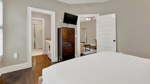 Quarto com cama, penteadeira, televisão e porta para um banheiro.