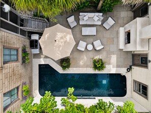 A rooftop pool area with a seating arrangement, a large umbrella, and surrounding greenery. - Stately Savannah Home w/ Saltwater Pool (Savannah)