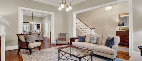 A spacious living room with a large sofa, a glass coffee table, and a staircase leading to another level.