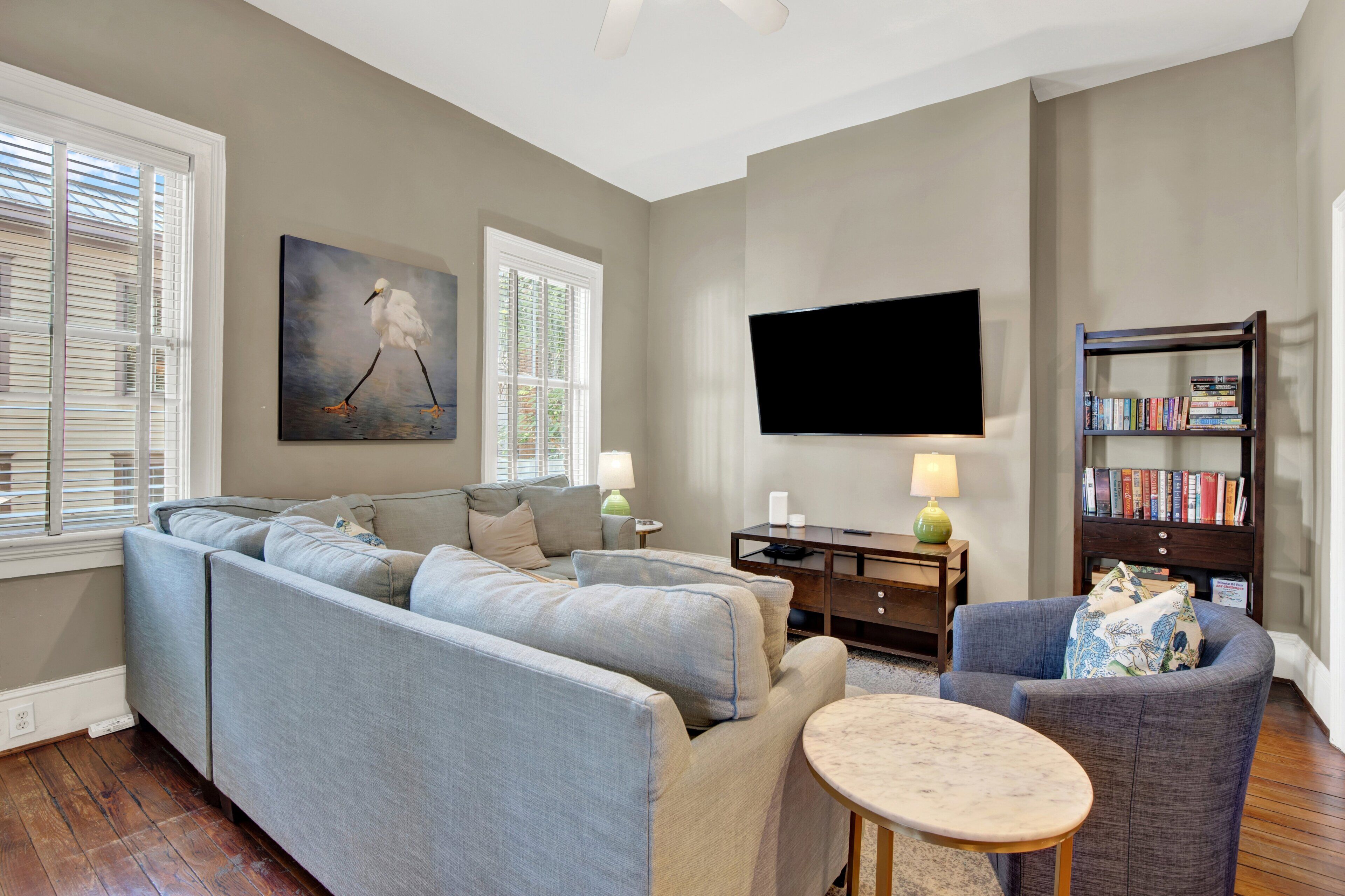 A living room with a sofa, a coffee table, a bookshelf, and a painting on the wall.
