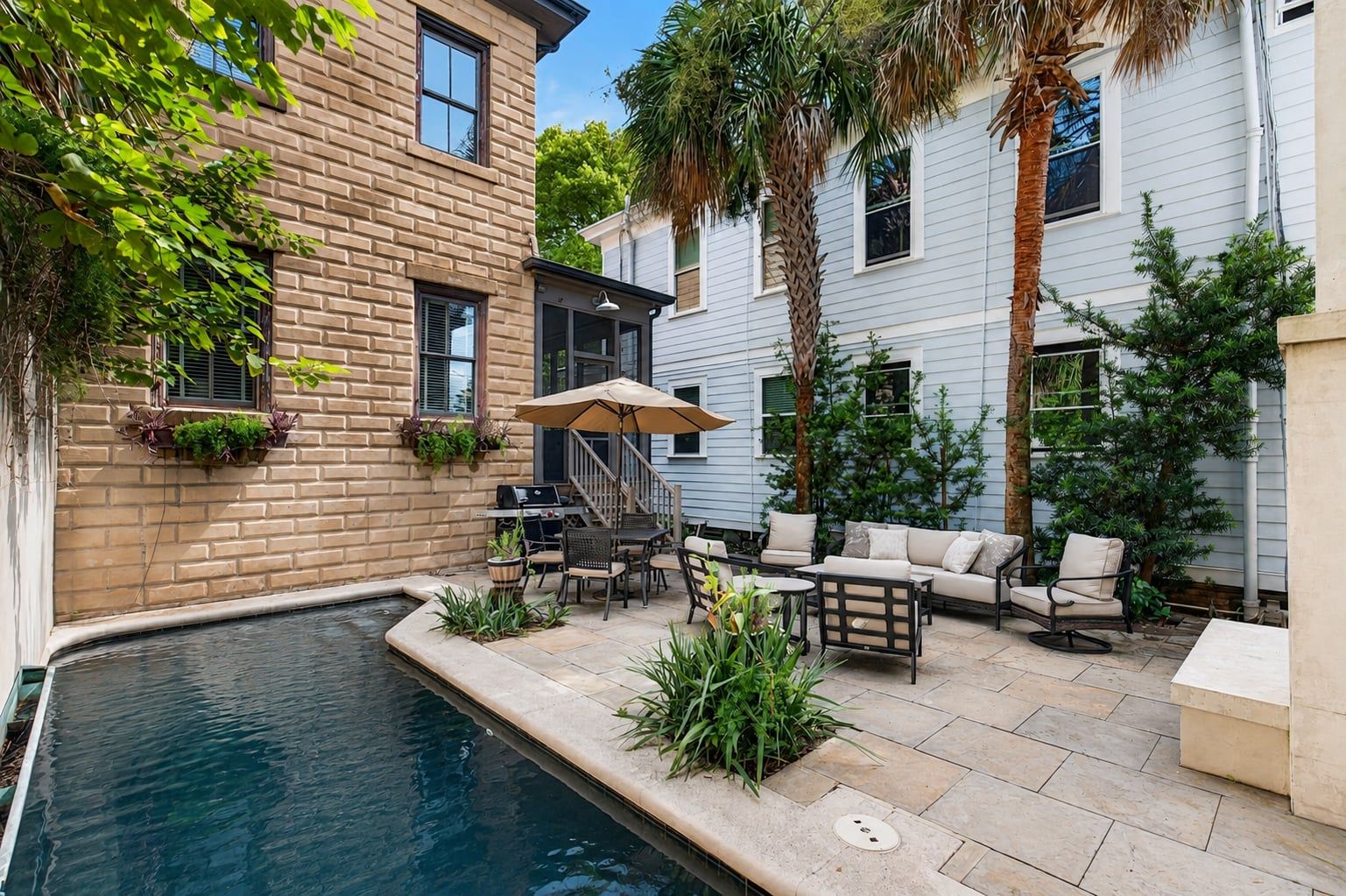 A courtyard with a swimming pool, outdoor furniture, and a grill area.