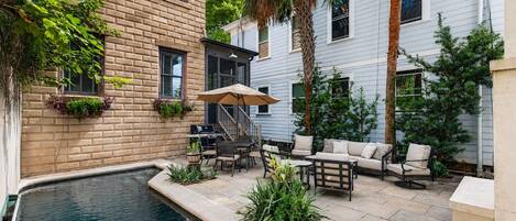 A courtyard with a swimming pool, outdoor furniture, and a grill area.