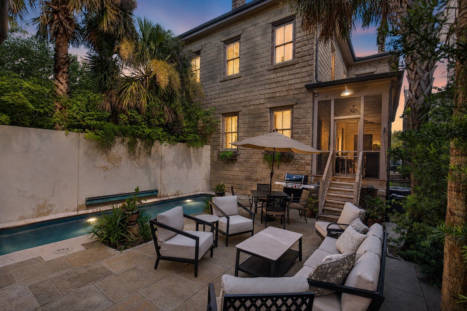 A backyard with a swimming pool, outdoor seating, and a barbecue area.