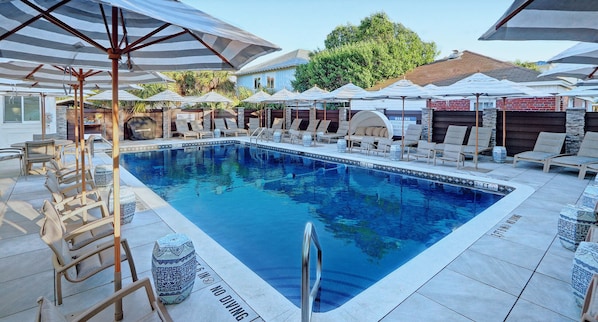 Piscina com estilo de resort, aquecida, com espreguiçadeiras e guarda-sóis.
