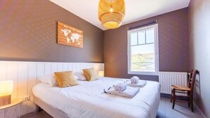 A neatly made bed with white linens and a world map artwork above it.