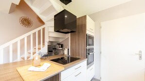 A modern kitchen with a wooden countertop, white cabinets, a black range hood, and a stainless steel oven.
