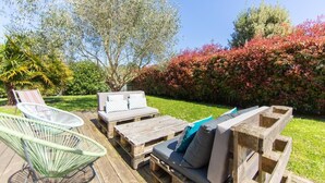 An outdoor seating area with a wooden bench and a metal chair.