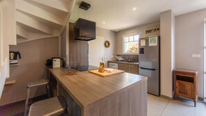 A modern kitchen with a central island, stainless steel appliances, and a built-in oven.