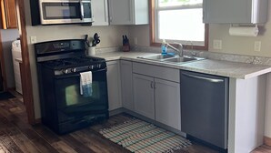 Une cuisine équipée d’une cuisinière, d’un four à micro-ondes, d’un évier et de placards.
