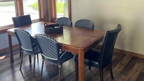 Un coin repas avec une table et des chaises en bois, un ventilateur de plafond et un panneau mural orné d’une illustration d’oiseau.